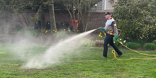 A technician applying a treatment to an outdoor area